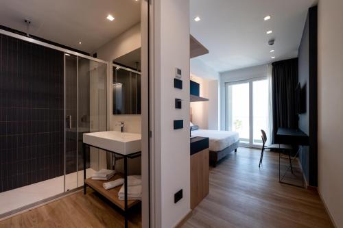 a bathroom with a sink and a shower and a bed at Hotel Sporting Riccione in Riccione
