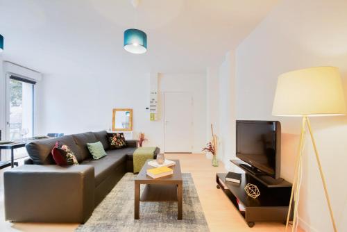 een woonkamer met een bank en een tv bij Appartement Balcon Garage Centre Gare in Nancy