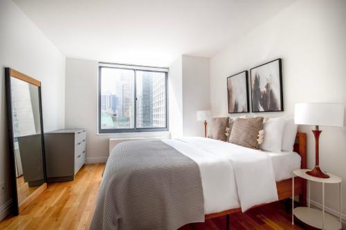 a white bedroom with a large bed and two windows at 1BR nr Broadway w Indoor pool Gym NYC-28 in New York