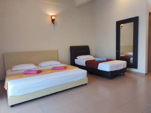 twee bedden in een kamer met een spiegel bij Gelama Resort Pasir Panjang in Port Dickson