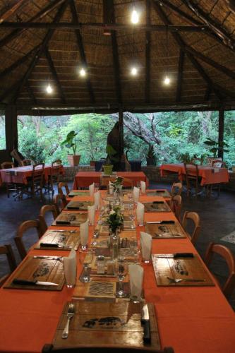 a long table in a restaurant with tables and chairs at Tamboti Bush Lodge in Dinokeng Game Reserve