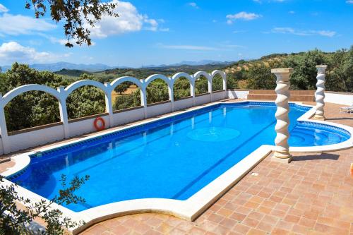 una piscina al aire libre con un patio de ladrillo y arcos blancos en Finca La Lola - Large House with private pool en Archidona