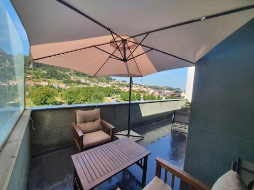 布埃烏的住宿－Alojamiento de relax y romanticismo !，阳台配有桌子、椅子和雨伞。