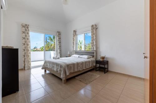 um quarto branco com uma cama e 2 janelas em Coral Beach Villa - Coral Bay em Coral Bay