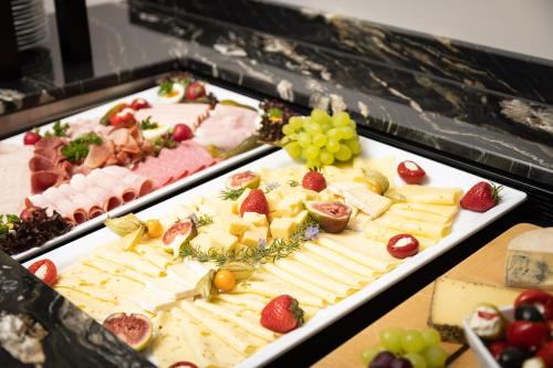 a display of cheese and fruit on a table at Hotel Donauhof in Deggendorf