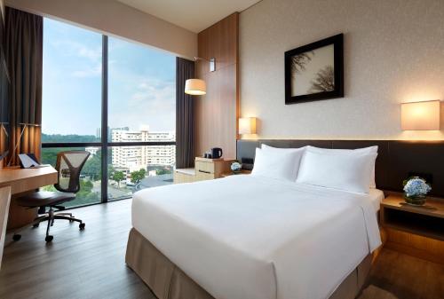 a hotel room with a large white bed and a desk at Momentus Hotel Alexandra in Singapore