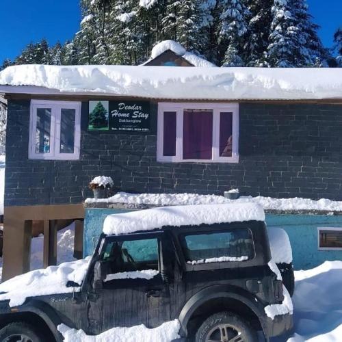a jeep parked in front of a snow covered building at Deodar Homestay Dakbangla-kufri in Shimla