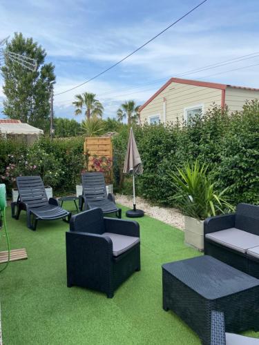 a patio with chairs and tables on green grass at Vos meilleures vacances au Montourey! in Fréjus