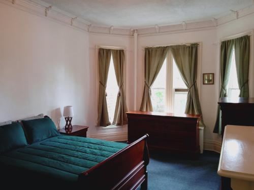 1 dormitorio con cama verde y ventanas en Mini Mansion Hotel affordable stays Plainfield NJ near public transportation, en Plainfield