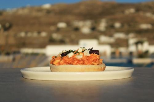 a sandwich on a white plate on a table at Adama Mykonos Boutique Hotel in Mikonos