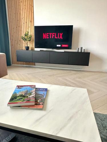 a living room with a tv and a book on a table at Luxusný apartmán na 21 poschodí s parkovaním zadarmo BA in Bratislava