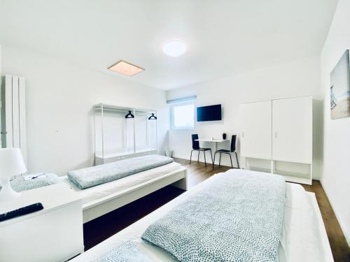 ein weißes Zimmer mit 2 Betten und einem Tisch in der Unterkunft Monteurzimmer ZIMMERzuVERMIETEN in Deitingen Industriestrasse in Deitingen