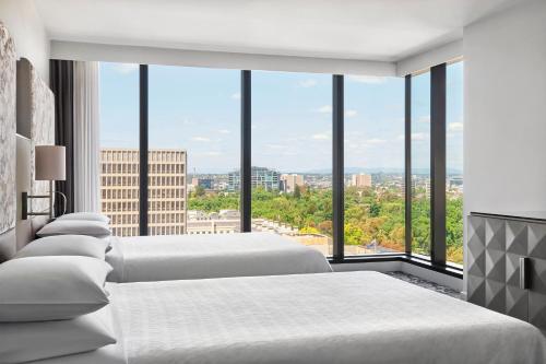 1 dormitorio con 3 camas y ventana grande en Sheraton Melbourne Hotel, en Melbourne