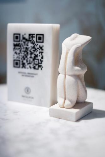 a white figurine next to a cup of coffee at Pafsilipon Suites in Ermoupoli