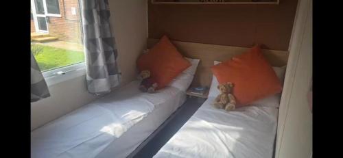 two teddy bears sitting on a bed next to a window at 192 Rickardos Holiday Lets 3 Bedroom caravan near Mablethorpe in Saltfleet