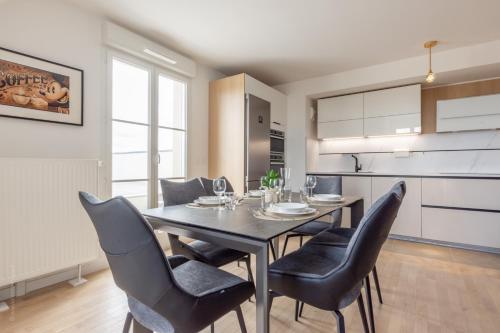 une salle à manger avec une table et des chaises noires dans l'établissement Sur un Nuage by Plaza, à Serris