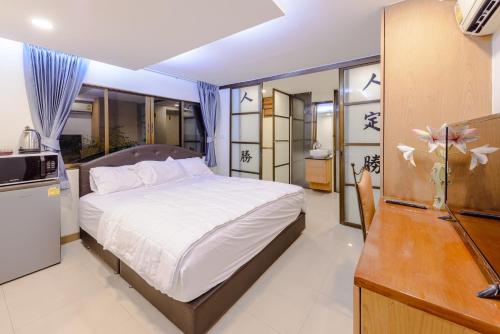 a bedroom with a large bed and a kitchen at Pasadena Lodge in Pattaya Central