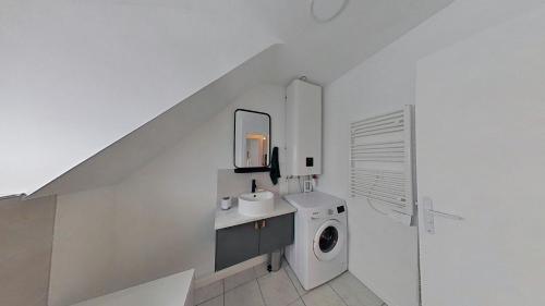 een witte badkamer met een wasmachine en een wastafel bij Vue sur Seine in Vernon