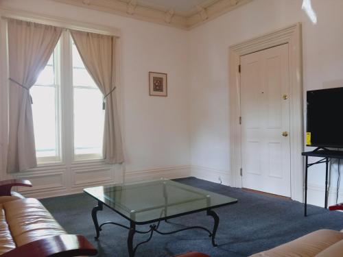a living room with a couch and a glass table at Mini Mansion Hotel near public transportation is the yellow and green house on the corner of 8th st and Madison avenue in Plainfield