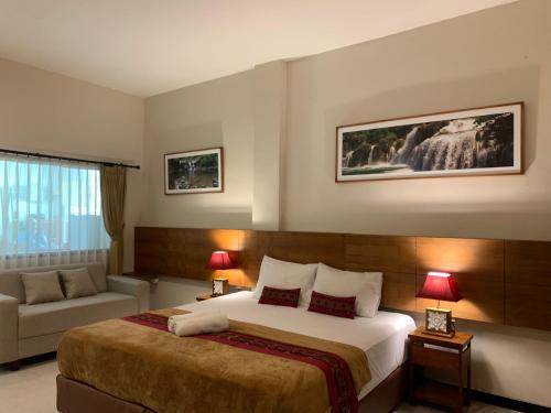 a hotel room with a bed and a couch at Kuta Suci Guesthouse in Kuta