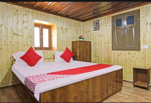 西姆拉的住宿－Deodar Homestay Dakbangla-kufri，一间卧室配有一张带红色枕头的大床