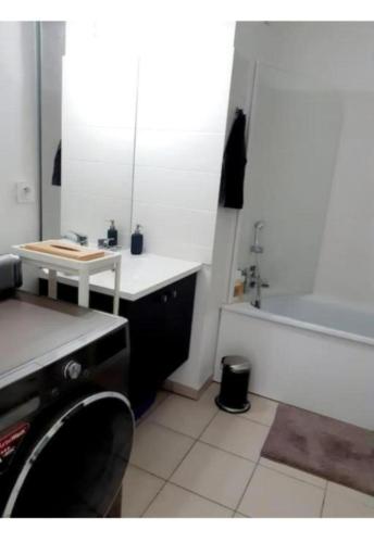 een badkamer met een bad, een wastafel en een tafel bij Casa Lione - Appartement Moderne à Décines in Décines-Charpieu