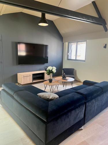- un grand canapé bleu dans le salon avec une télévision dans l'établissement Le Loft Manhattan, en centre ville, proche Sainte Bernadette avec Parking, PRIMO C0NCIERGERIE, à Nevers