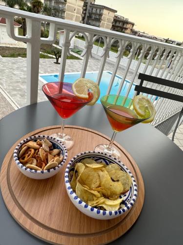 two cocktails and chips on a table on a balcony at Rosy's House in Scafati