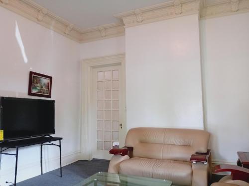 a living room with a couch and a television at Mini Mansion Hotel near public transportation is the yellow and green house on the corner of 8th st and Madison avenue in Plainfield