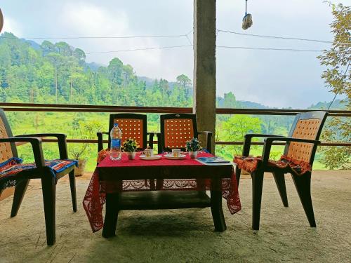 a table and chairs on a porch with a view at Bholenath Homestay Dalhousie in Dalhousie