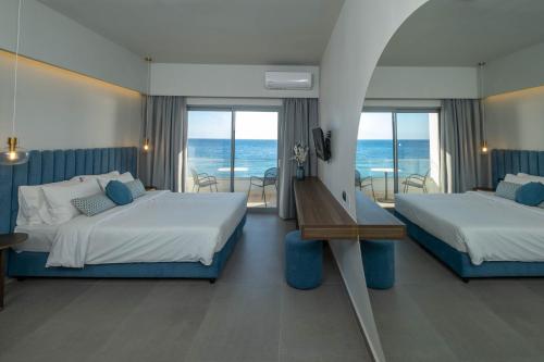 a hotel room with two beds and a view of the ocean at Mochlos Blue in Mochlos