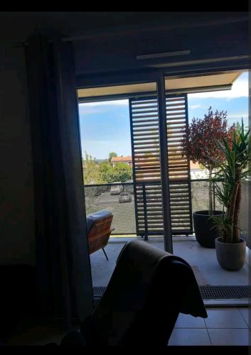 een kamer met een raam met planten en een stoel bij Casa Lione - Appartement Moderne à Décines in Décines-Charpieu