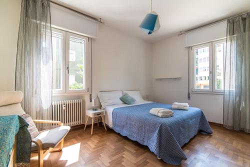 a bedroom with a bed and a chair and windows at enJoy Home - Bilocale sulle Riviere a due passi dalla Specola in Padova