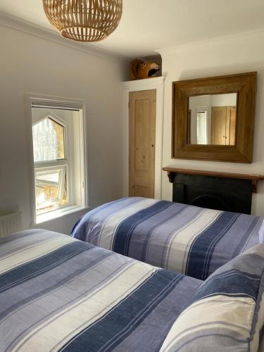 a bedroom with two beds and a mirror at Cozy coastguard cottage with sea views in East Cowes