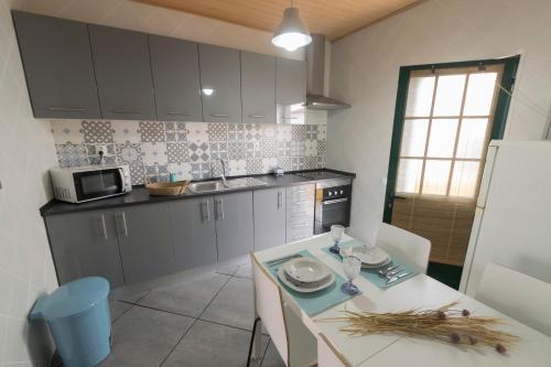 a kitchen with a table with chairs and a microwave at Casa da Avó in Alcácer do Sal