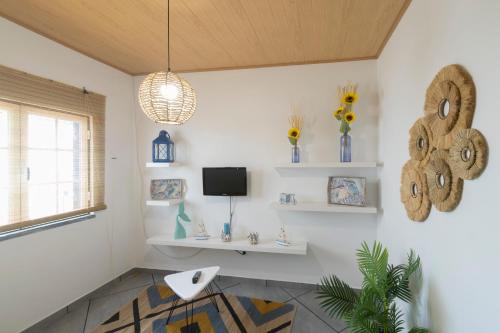 a room with white walls and a tv and shelves at Casa da Avó in Alcácer do Sal