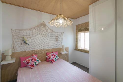 um quarto com uma cama com almofadas cor-de-rosa e um lustre em Casa da Avó em Alcácer do Sal