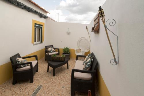 a patio with chairs and tables and an umbrella at Casa da Avó in Alcácer do Sal