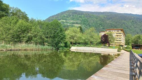 a wooden bridge over a lake with a building in the background at ROBERTO Haus KMB Seeappartement direkt am Ossiacher See mit Hallenbad in Tschöran