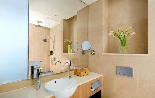 La salle de bains est pourvue d'un lavabo et d'un miroir. dans l'établissement Momentus Hotel Alexandra, à Singapour