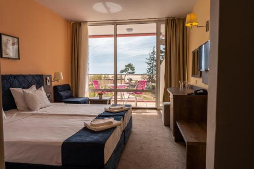 Flamingo Beach Hotel في ساني بيتش: غرفه فندقيه بسرير وشرفه