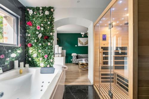 La salle de bains est pourvue d'une baignoire avec des fleurs sur le mur. dans l'établissement Sauna, jacuzzi, terrasse et parking, à Rouen