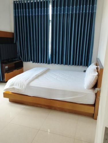 Schlafzimmer mit einem Bett und einem Fenster mit blauen Vorhängen in der Unterkunft Villa Sealinks Phan Thiết 3PN View bien in Ấp Ngọc Hải