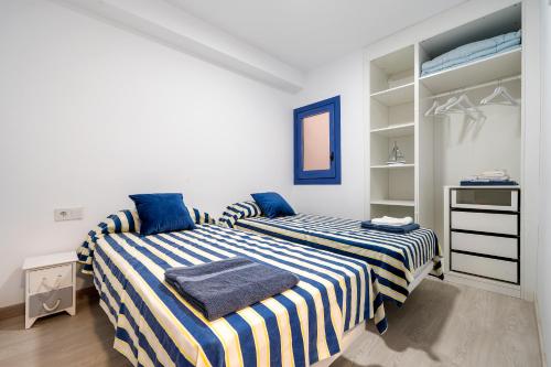 a bedroom with two beds with blue and white stripes at La Casa del Pescador Calafellmar in Calafell