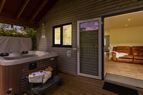 a bathroom with a tub and a sliding glass door at The Clover Lodge, Red Lake Farm Nr Glastonbury in Somerton