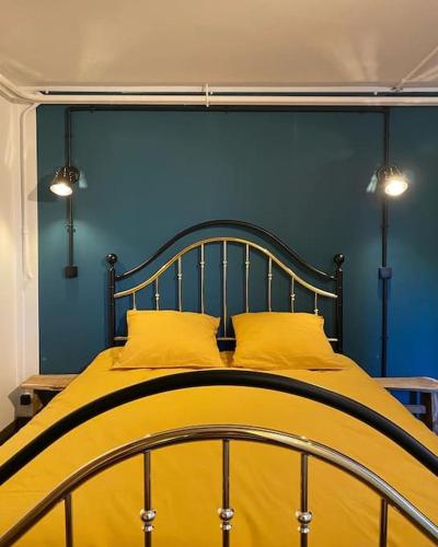 - un lit avec des oreillers jaunes et un mur bleu dans l'établissement L’expérience BrocAndBric, à Amboise