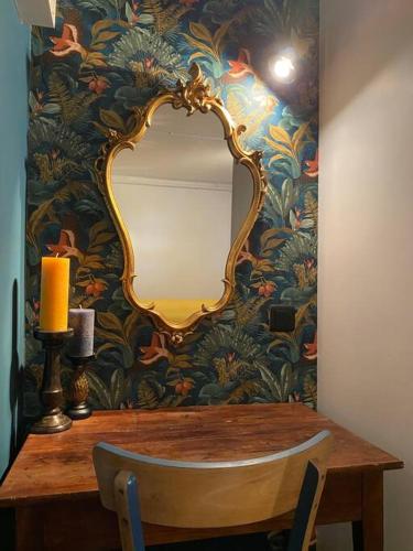 un miroir sur un mur à côté d'une table avec une bougie dans l'établissement L’expérience BrocAndBric, à Amboise