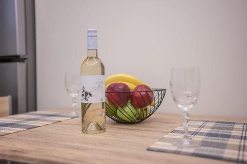 a bottle of wine and a bowl of fruit on a table at Aurora apartments Room 1 in Marmari
