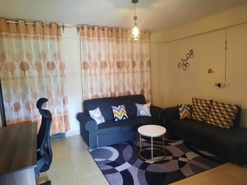 ein Wohnzimmer mit einem blauen Sofa und einem Tisch in der Unterkunft La Casa Nakuru in Nakuru