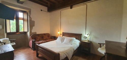 a bedroom with a bed and a chair and a couch at Monasterio y Pensión de Moraime in Muxia